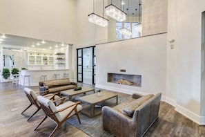 Amplia sala de estar con chimenea, muebles de madera y una cocina al fondo.