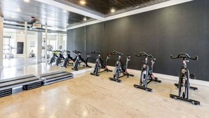 A gym with stationary bikes arranged in a row, a polished floor, and a dark wall.