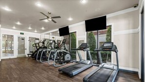 Una palestra con tapis roulant, macchinari ellittici e una ventola a soffitto.