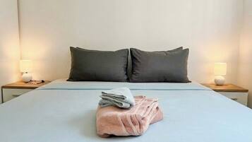 Una habitación de hotel con una cama bien hecha, dos lámparas de noche y una toalla doblada sobre la cama.