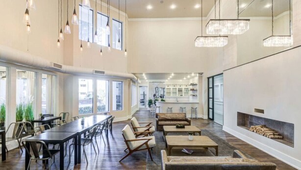 A spacious lounge area with a long table, sofas, and a fireplace.