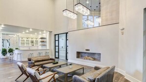 A spacious living room with a fireplace, wooden furniture, and a kitchen area in the background.