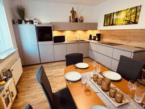 Eine moderne Küche mit Essbereich, ausgestattet mit Mikrowelle, Herd und Kaffeemaschine.