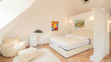 Un dormitorio con una cama, una silla, un aparador y un cuadro en la pared.