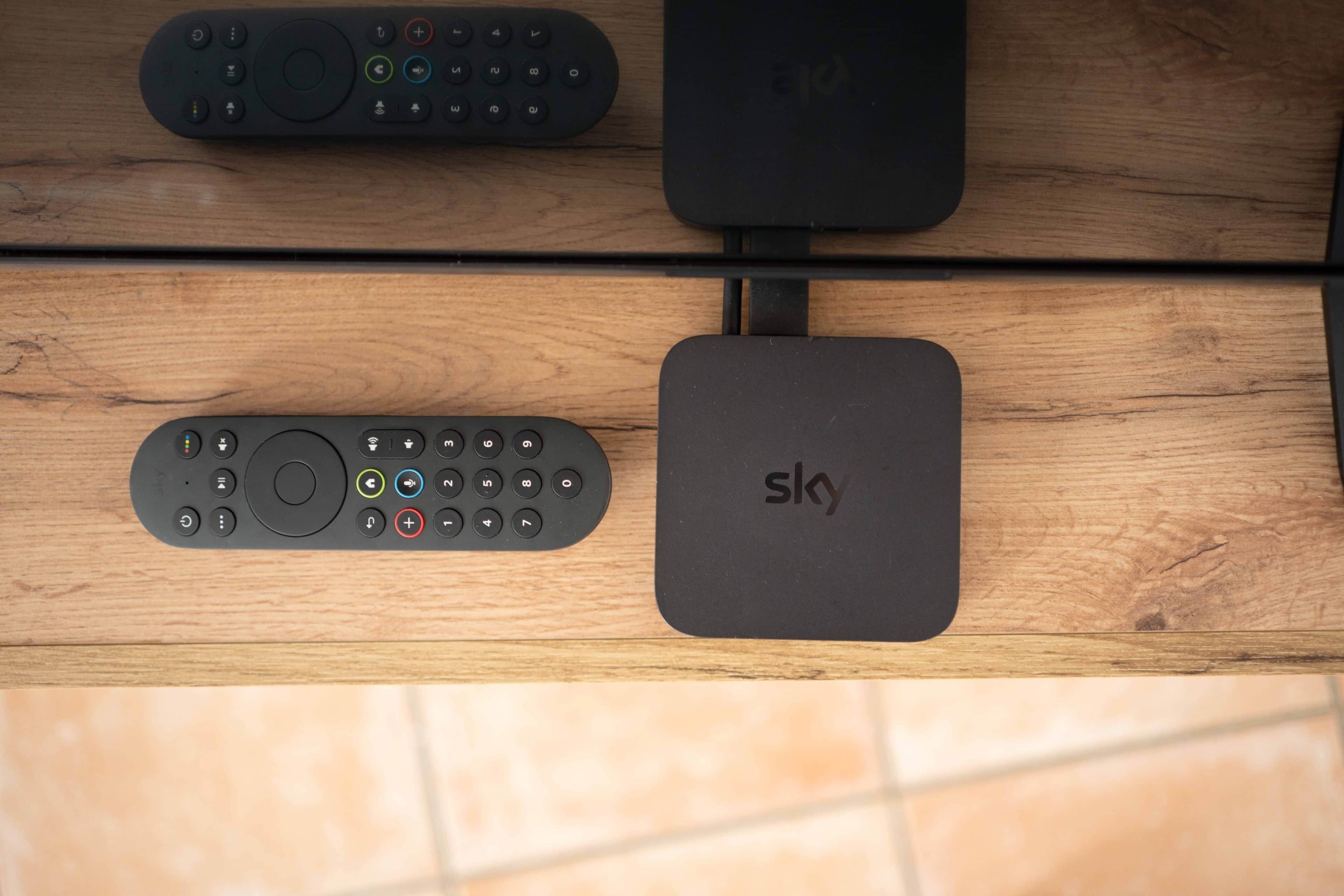 En träyta med tre fjärrkontroller och en Sky-enhet.