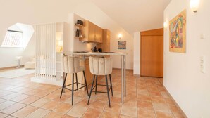 A modern kitchen with a bar area, wooden cabinets, and a dining table. - Stylish Apartment | WiFi, Sky TV & Nespresso (Sobernheim)