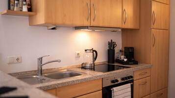 Eine Küche mit Holzausstattung, einem Edelstahlspülbecken, einer Kaffeemaschine und einem Backofen.