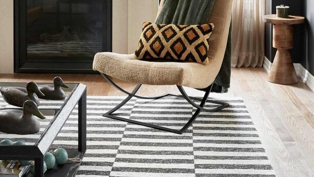 Una sala de estar moderna con chimenea, un sillón cómodo, un tapiz estampado y una lámpara de techo decorativa con adornos de asta.