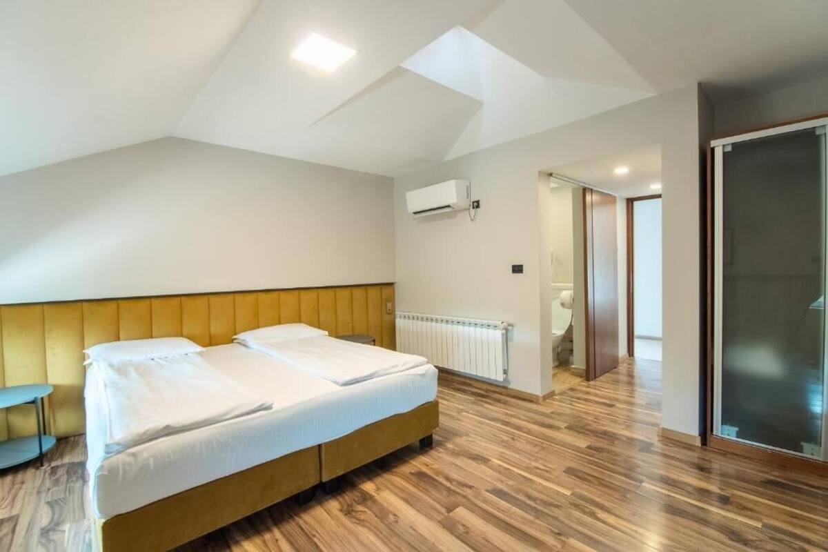 Un dormitorio con cama, mesita de noche, aire acondicionado y radiador.
