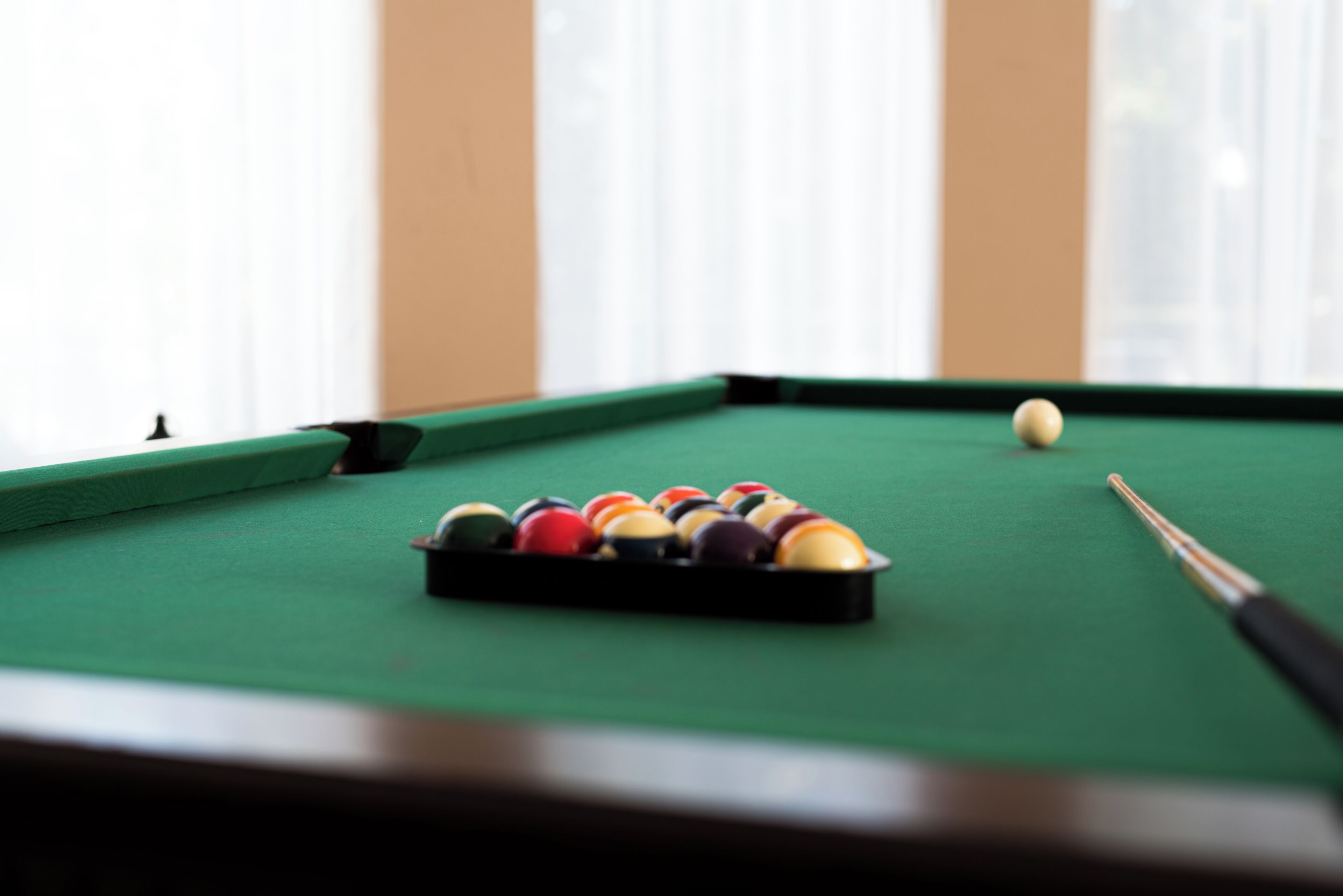 A pool table with balls and a cue stick.