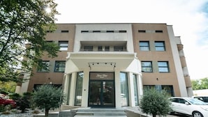A hotel entrance with a modern facade, a central entrance, and a small garden area with steps leading up to the door. - Hotel Vital (Băile Felix)