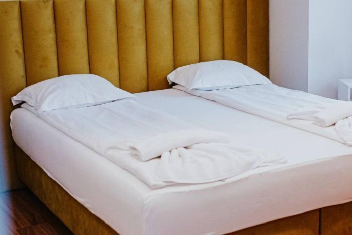 Una cama doble con cabecera de madera y ropa de cama blanca.