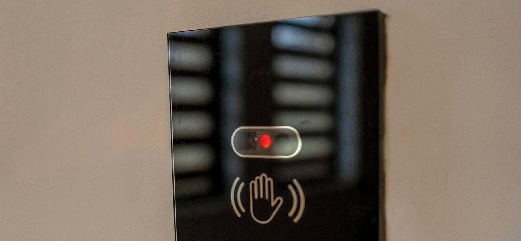A door with a red light and a hand symbol, indicating a sensor or intercom system.