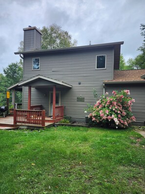 Ein zweistöckiges Haus mit einer Veranda und einem kleinen Garten.
