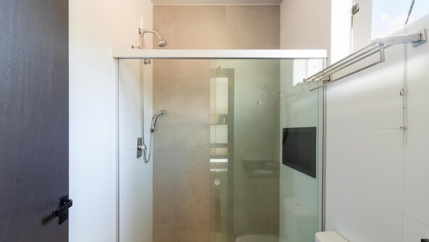 A modern bathroom with a glass shower enclosure, a toilet, and a sink. - Functional and Well-located Studios in Blumenau - OLA (Blumenau)