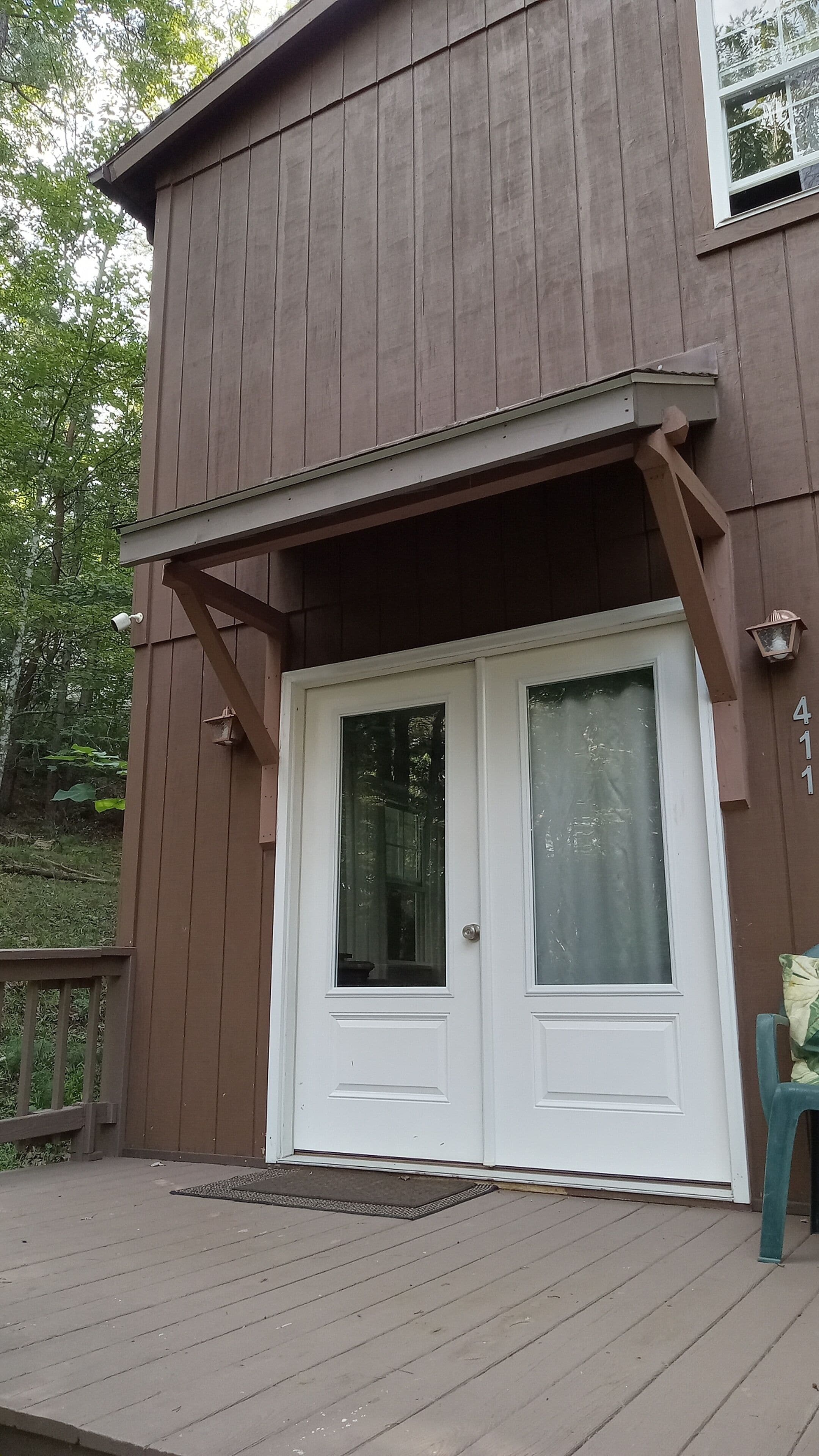A two-story building with a brown exterior, a white front door, and a small porch area.