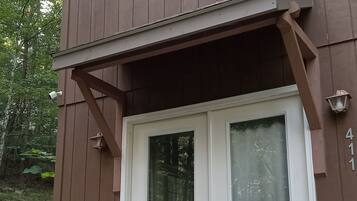 A two-story building with a brown exterior, a white front door, and a small porch area.