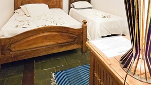 A bedroom with two wooden beds, a chandelier, a painting, a lamp, and a blue mat on the floor. - Pouso Canto de Minas (Tiradentes)