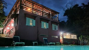 A two-story building with a swimming pool, outdoor seating, and a covered area. - Pouso Canto de Minas (Tiradentes)