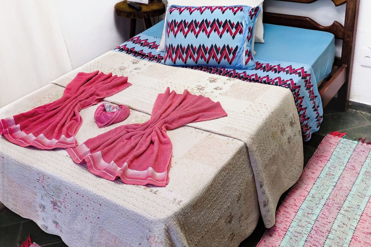 Uma cama com colcha estampada, almofadas e abajur.