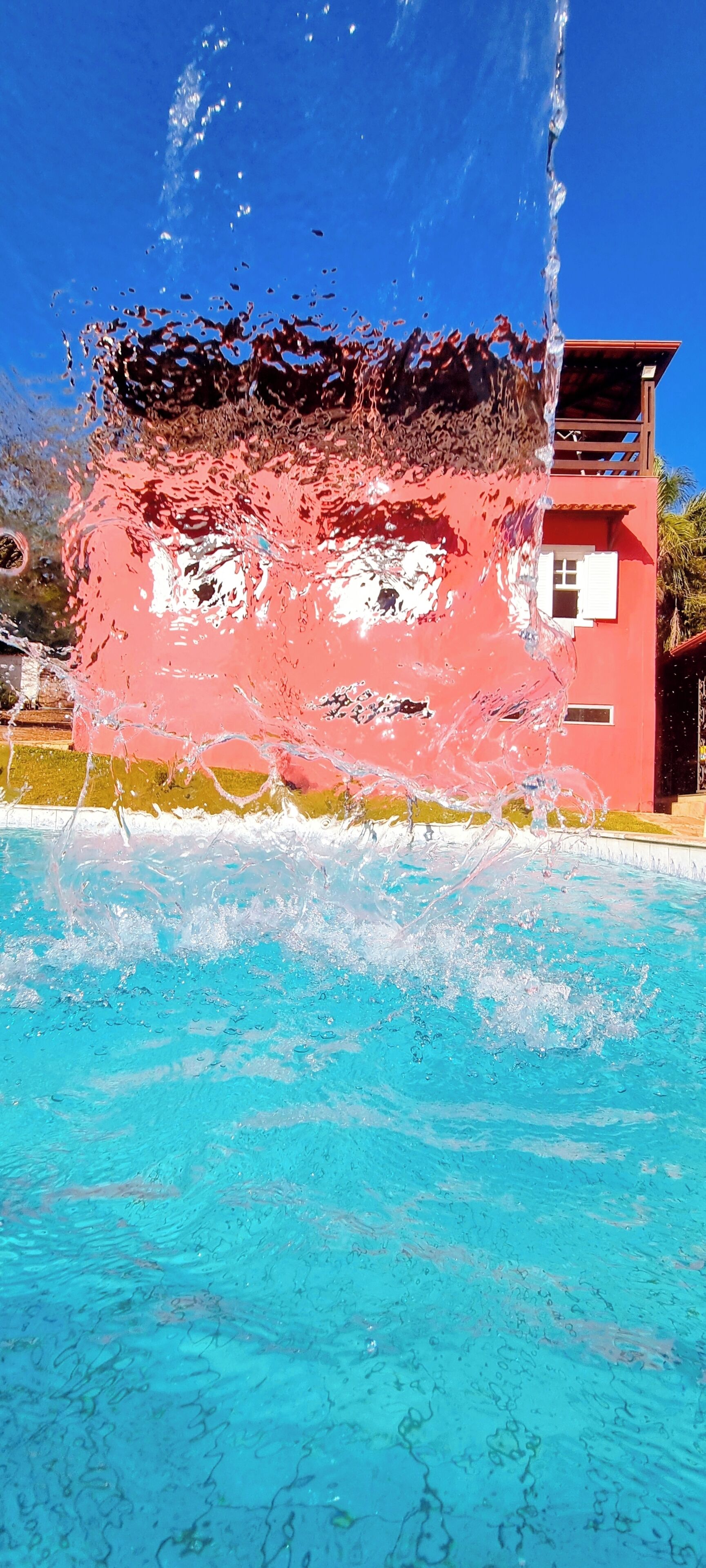 A pool with clear water and a red building in the background.