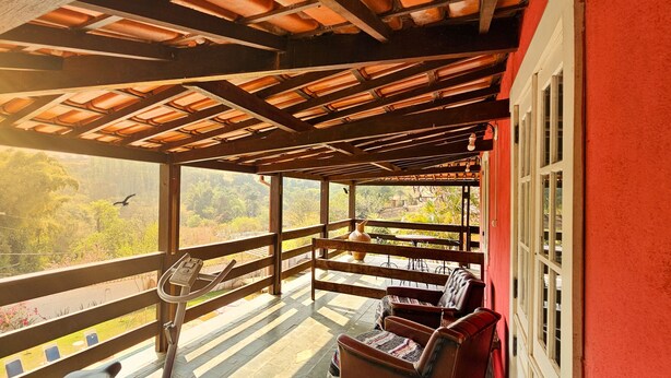 A covered balcony with a wooden railing, a bicycle, and a table with chairs. - Pouso Canto de Minas (Tiradentes)