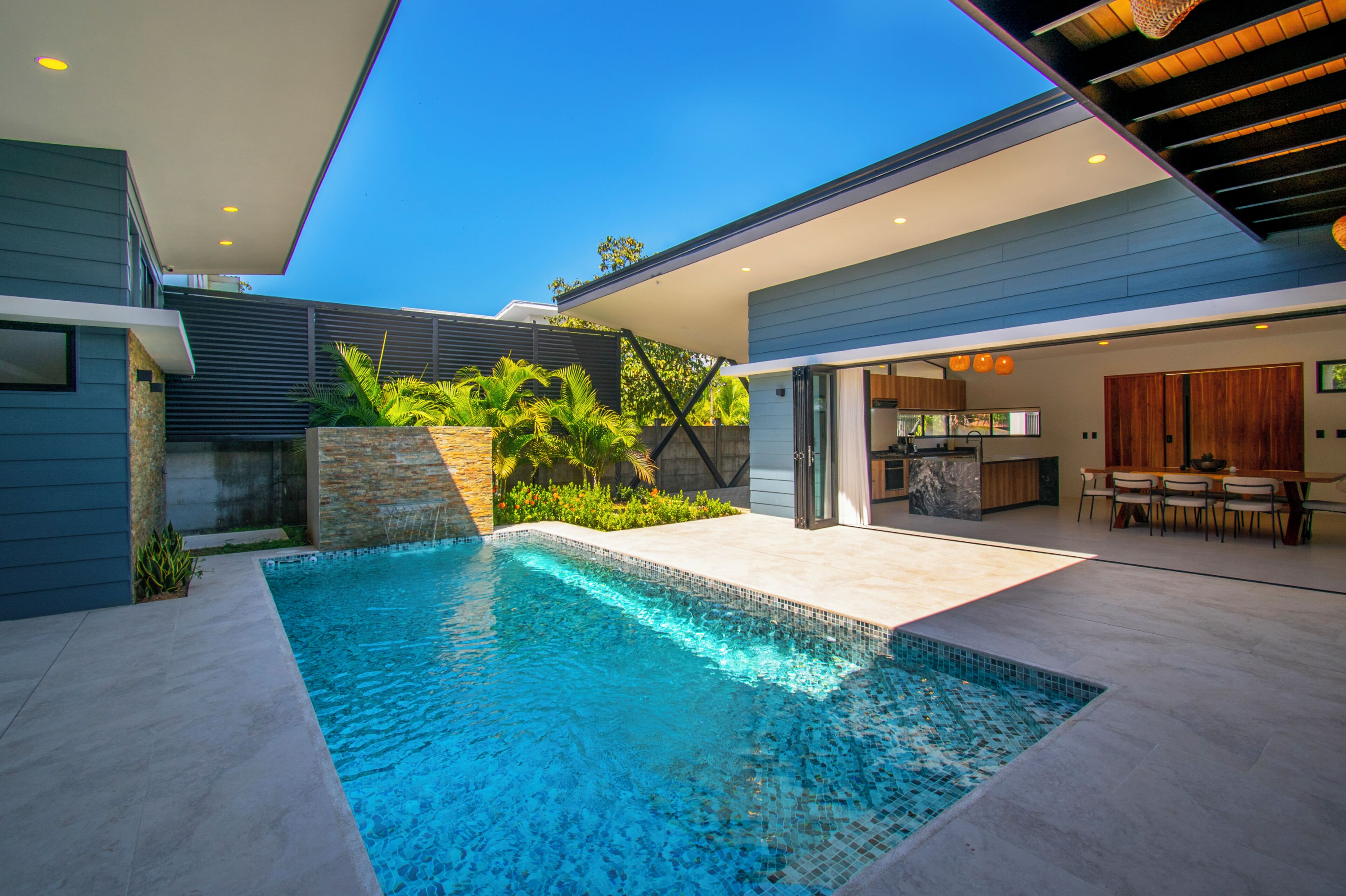 A modern house with a swimming pool, a dining area, and a kitchen.