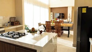 A modern kitchen with a central island, dining area with wooden chairs, and a black refrigerator. - Family House w Private Pool Rooftop & BeachClub (Solidaridad)