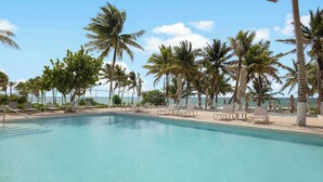 A swimming pool with lounge chairs and palm trees, overlooking the ocean. - Family House w Private Pool Rooftop & BeachClub (Solidaridad)