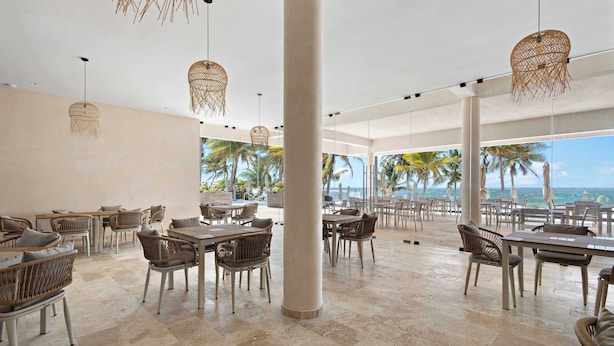 A spacious outdoor dining area with wicker furniture and hanging lights, overlooking a beach with palm trees. - Family House w Private Pool Rooftop & BeachClub (Solidaridad)