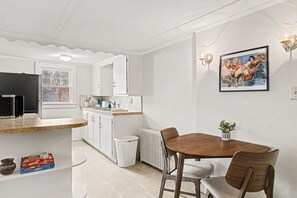 A modern kitchen with white cabinets, a built-in stove, and a dining area with a wooden table and chairs.