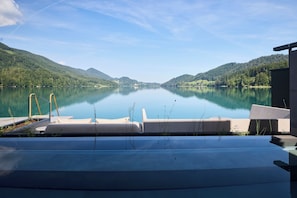 A serene lakeside view with a dock extending into the water, surrounded by lush green hills. - Vogl's Nest  (Fuschl am See)