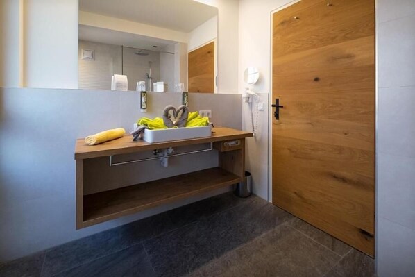 Ein modernes Badezimmer mit einem Holzlagerfläschchen, einem Spiegel und einem Handtuch.
