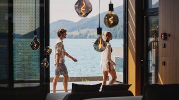A modern interior with a large window overlooking a body of water and mountains.