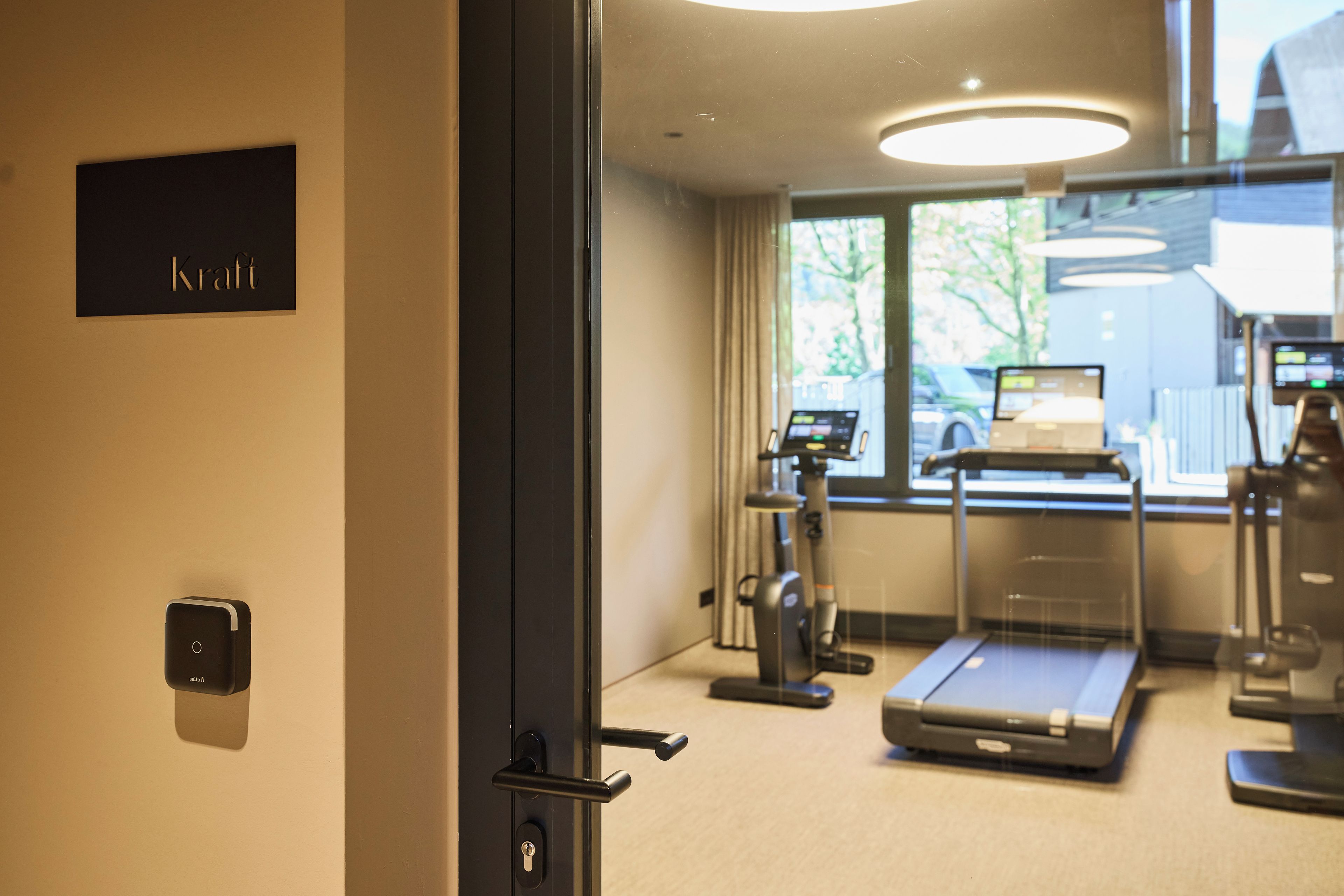 A modern fitness room with exercise equipment, a treadmill, and a wall-mounted sign.