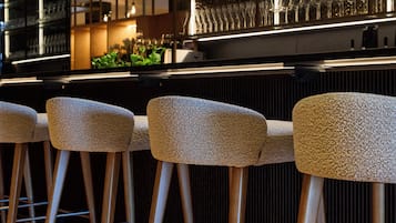 A bar area with wooden stools and a glass display of glasses.