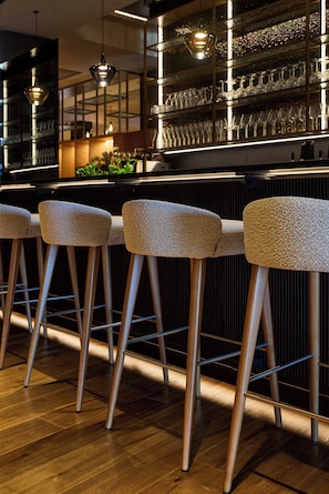 A bar area with wooden stools and a glass display of glasses. - Vogl's Nest (Fuschl am See)
