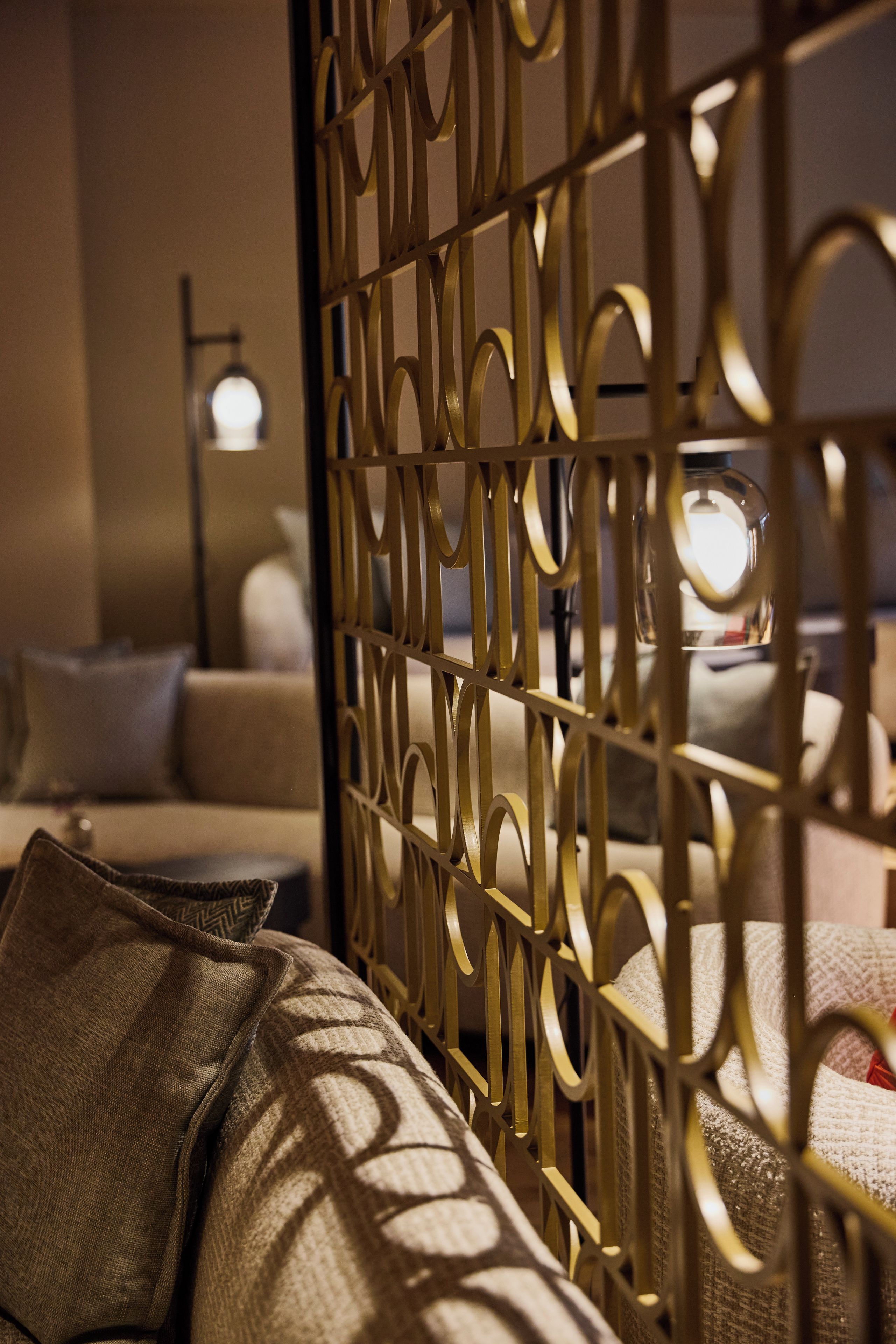 A room with a patterned partition, a sofa, and a lamp.