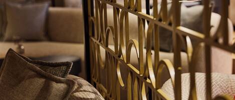 A room with a patterned partition, a sofa, and a lamp.