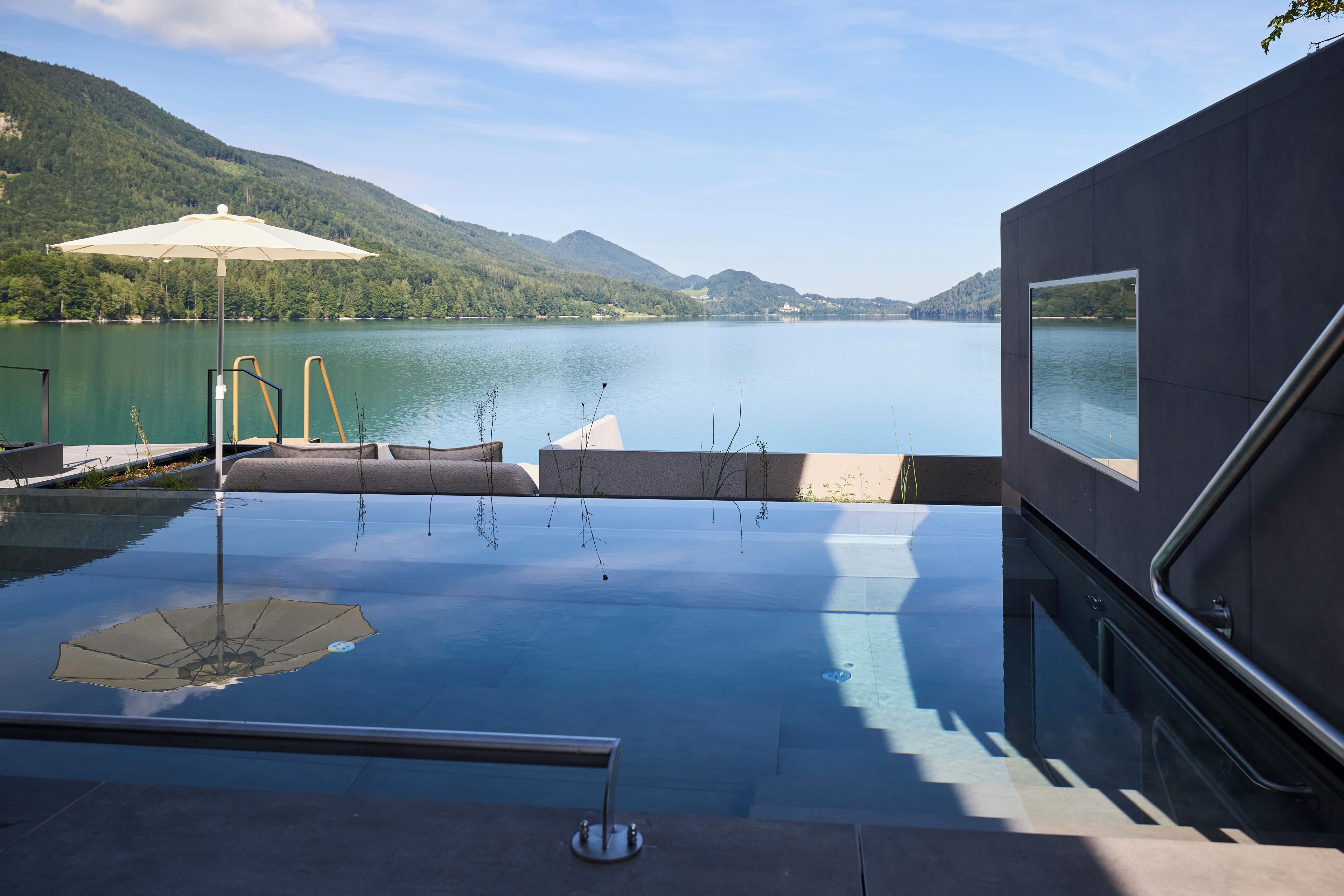 Una piscina infinita con vista a un lago y montañas.