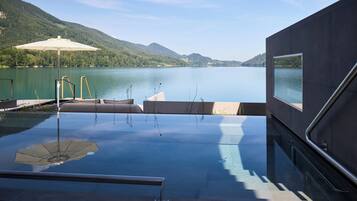 Una piscina infinita con vista a un lago y montañas.