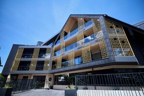 Un edificio moderno con numerosi balconi, ampie finestre e un ingresso recintato.