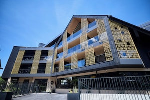 A modern building with multiple balconies, large windows, and a gated entrance.