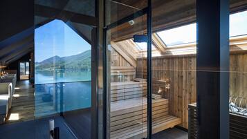 A modern interior with a glass wall offering a view of a lake and mountains.