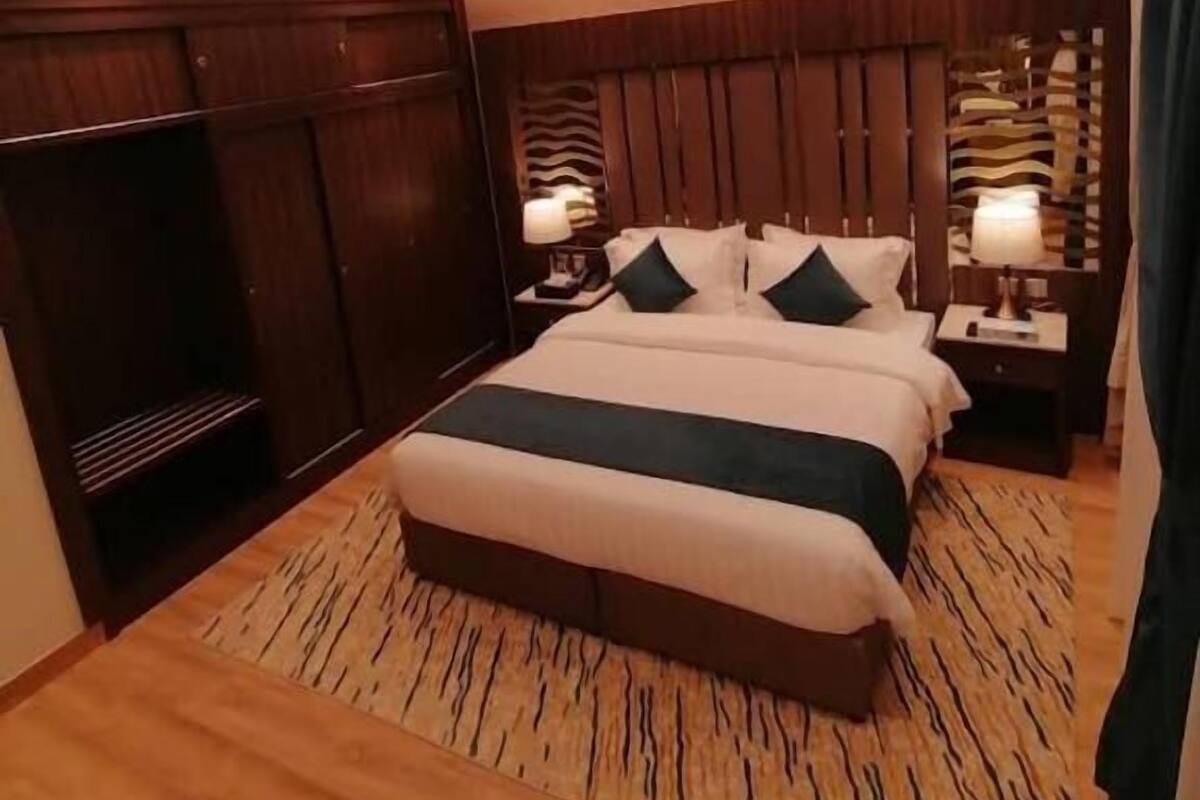 Une chambre d’hôtel avec un grand lit, une tête de lit en bois et une armoire.