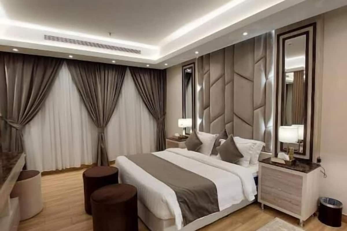 Une chambre moderne avec un grand lit, des tables de chevet, un miroir et un plancher en bois.