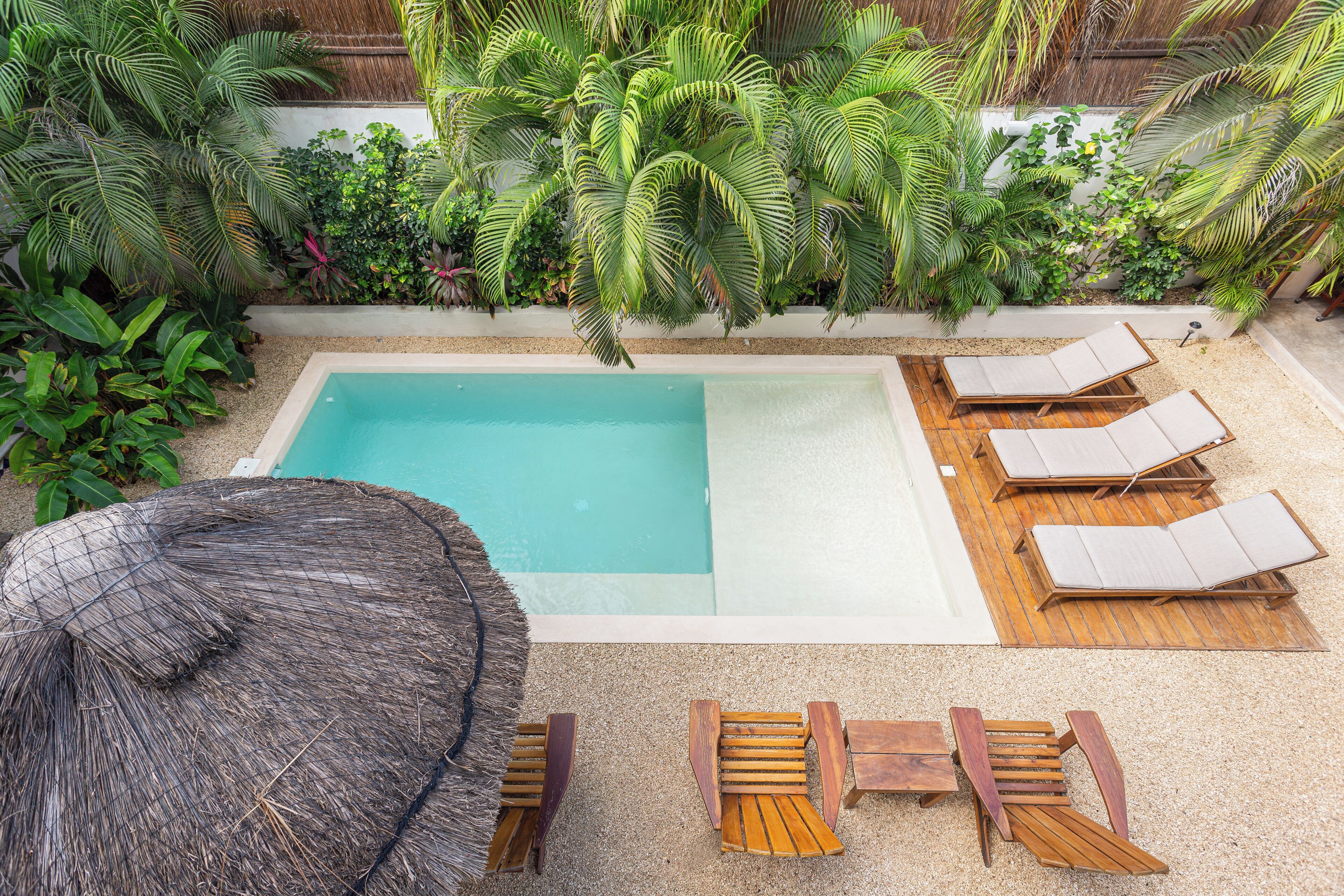 Ein Pool mit Liegestühlen und einem Strohdachschirm.