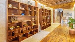 A hallway with wooden shelving units filled with various decorative items, a staircase in the background, and a potted plant on the right. - 9BR Villa | Sleeps 24 | Private Pool + Rooftop | Concierge & Breakfast Included (Tulum)