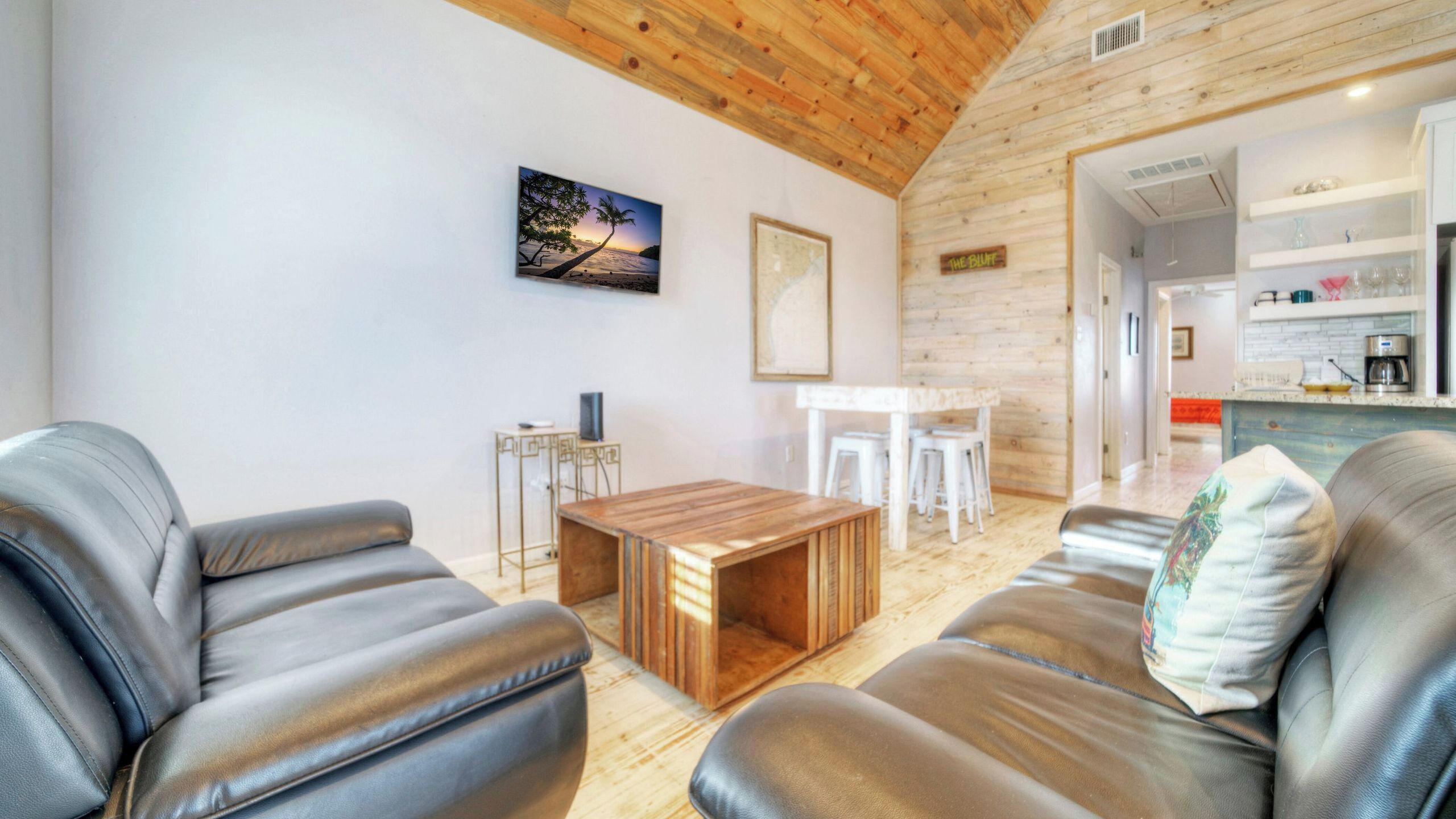 Un salon moderne avec des canapés en cuir, une table basse en bois et un tableau accroché au mur.