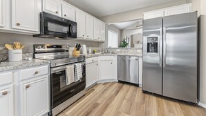 A modern kitchen with white cabinets, stainless steel appliances, and a wooden floor. - Lake Haven Retreat - Spacious 3BR Family Escape Near Lake Lewisville (Little Elm)